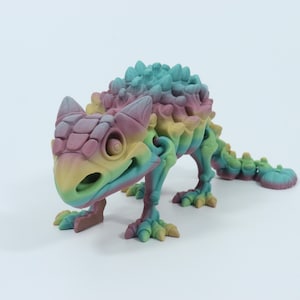 Peut inclure: Un dinosaure jouet imprimé en 3D de couleur arc-en-ciel avec un dos hérissé et une longue queue.