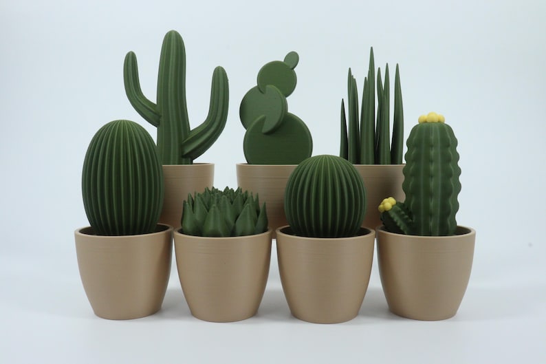May include: A collection of green cactus sculptures in various shapes, including oval, round, and columnar, each potted in a beige container. The cacti have detailed textures and are arranged against a white background.