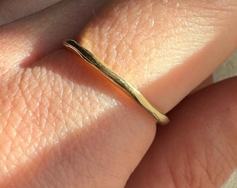 May include: A simple gold band ring with a hammered texture.