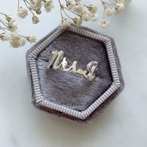 以下が含まれることがあります： グレーのベルベット製のリングボックスに、