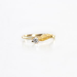 May include: A gold ring with a single diamond and a textured gold leaf design.