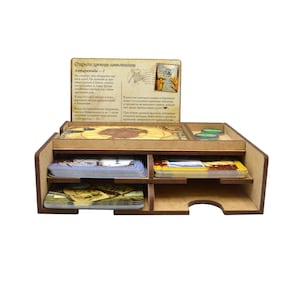 Könnte beinhalten: Holzorganizer mit mehreren Fächern zum Verstauen von Spielkarten und Spielsteinen. Der Organizer hat eine braune Oberfläche und trägt ein Etikett mit der Aufschrift "Откуда древнюю почту присылали?"  Der Organizer ist für die Aufbewahrung von Spielkomponenten für das Brettspiel "Откуда древнюю почту присылали?" konzipiert.