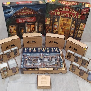 May include: A wooden game organiser set for the board game "Tavern of Tiefenthal". The set includes multiple compartments for storing game components, such as cards and tokens. The organiser is made of natural wood and has a light brown finish.