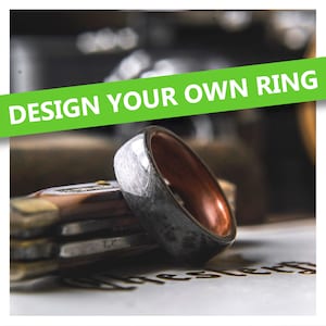 May include: A close-up of a silver and brown ring with a brushed metal finish. The ring is on a wooden surface with the text "DESIGN YOUR OWN RING" in green letters.