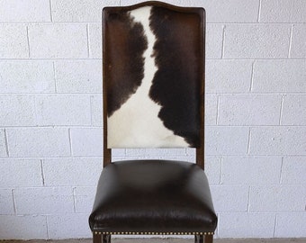 May include: A brown wooden chair with a cowhide seat and back. The chair has a traditional design with a curved back and a slightly flared base.
