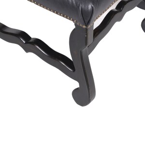 Pu&ograve; includere: Primo piano delle gambe in legno nero di una sedia con un design intagliato. Le gambe sono curve e hanno un ricciolo decorativo in basso.
