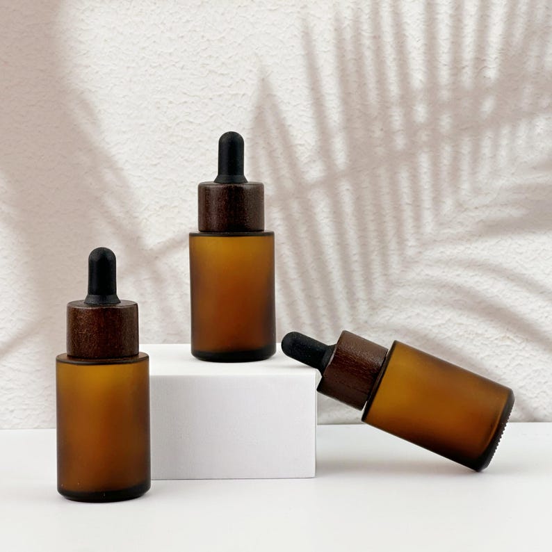 Three brown dropper bottles with natural wooden lids, arranged in an orderly manner.