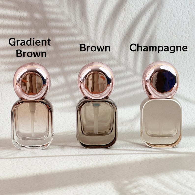 Assorted 20ml perfume bottles in different finishes (champagne gold, clear, frosted white) with rose gold caps and white spray pumps displayed.