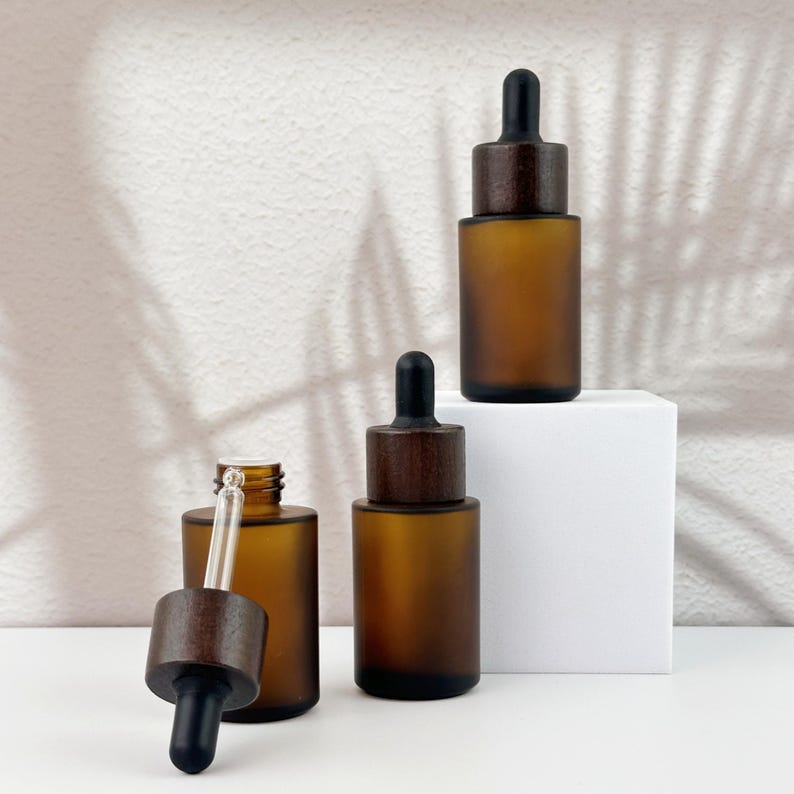 Three brown dropper bottles with natural wooden lids, arranged in an orderly manner, and the wooden lid of one of them has been removed.