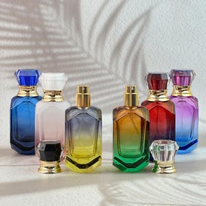 Pode incluir: Uma variedade de frascos de perfume coloridos com formas geométricas. As garrafas apresentam um gradiente de cores, incluindo azul, rosa, amarelo, verde, vermelho e roxo. Cada garrafa tem uma gola dourada e uma tampa de cristal.