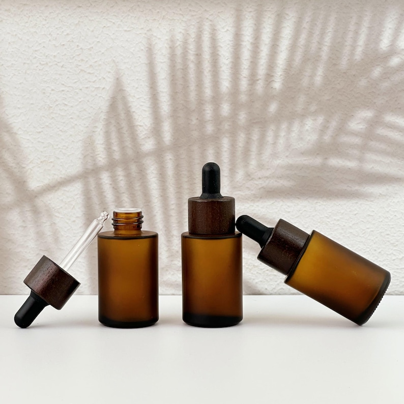Three brown dropper bottles with natural wooden lids, arranged in an orderly manner, and the wooden lid of one of them has been removed.