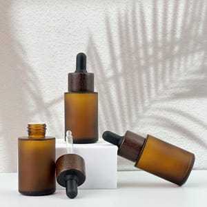 Three brown dropper bottles with natural wooden lids, arranged in an orderly manner, and the wooden lid of one of them has been removed.