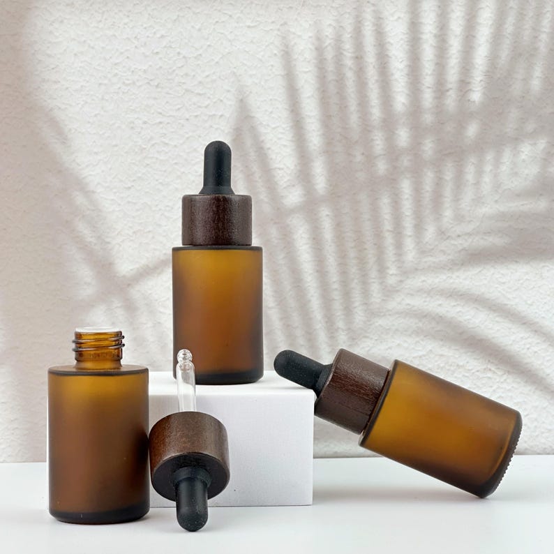 Three brown dropper bottles with natural wooden lids, arranged in an orderly manner, and the wooden lid of one of them has been removed.