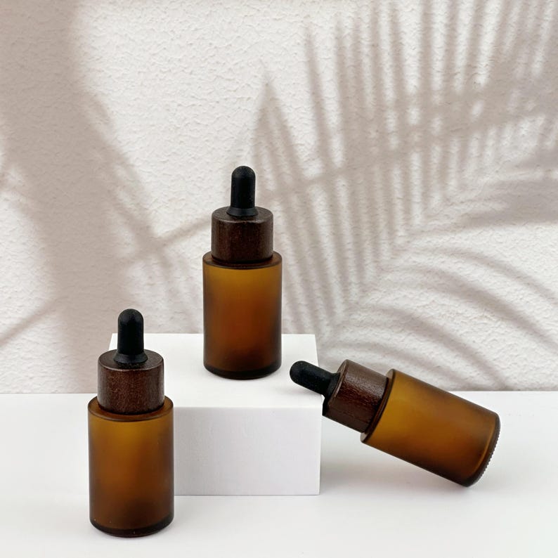 Three brown dropper bottles with natural wooden lids, arranged in an orderly manner.