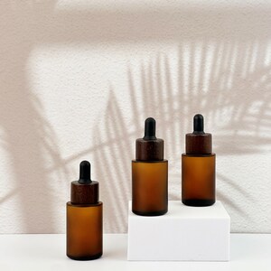 Three brown dropper bottles with natural wooden lids, arranged in an orderly manner.