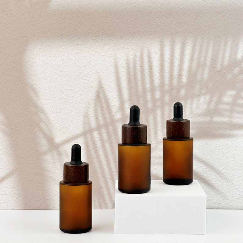 Three brown dropper bottles with natural wooden lids, arranged in an orderly manner.