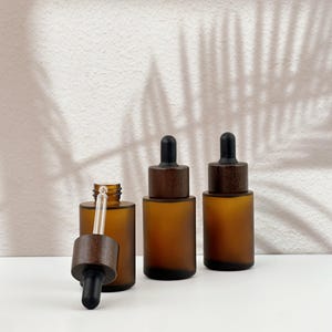 Three brown dropper bottles with natural wooden lids, arranged in an orderly manner, and the wooden lid of one of them has been removed.