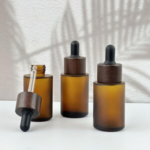 Three brown dropper bottles with natural wooden lids, arranged in an orderly manner, and the wooden lid of one of them has been removed.