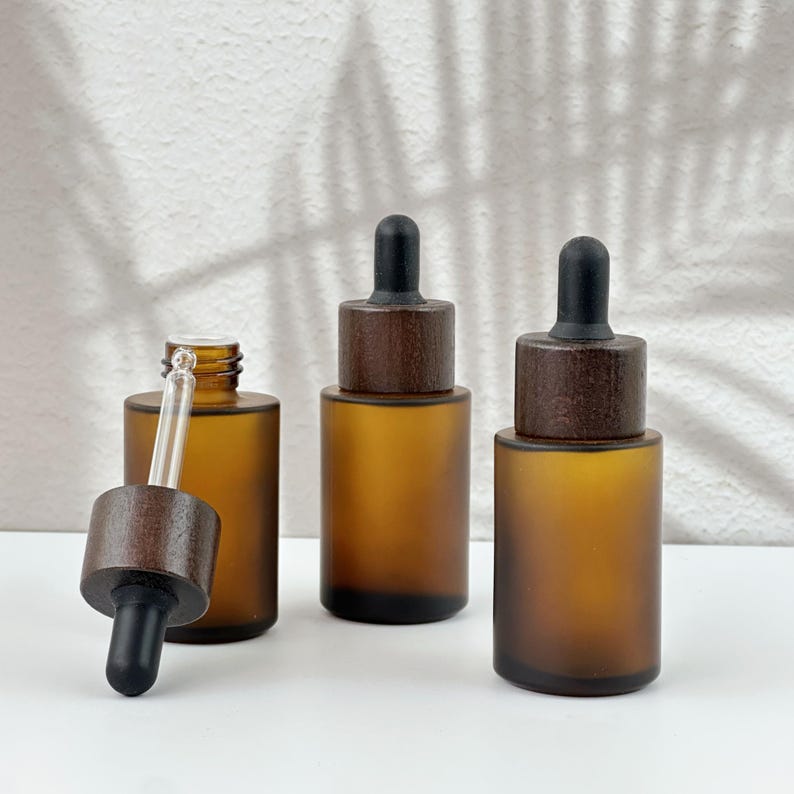 Three brown dropper bottles with natural wooden lids, arranged in an orderly manner, and the wooden lid of one of them has been removed.