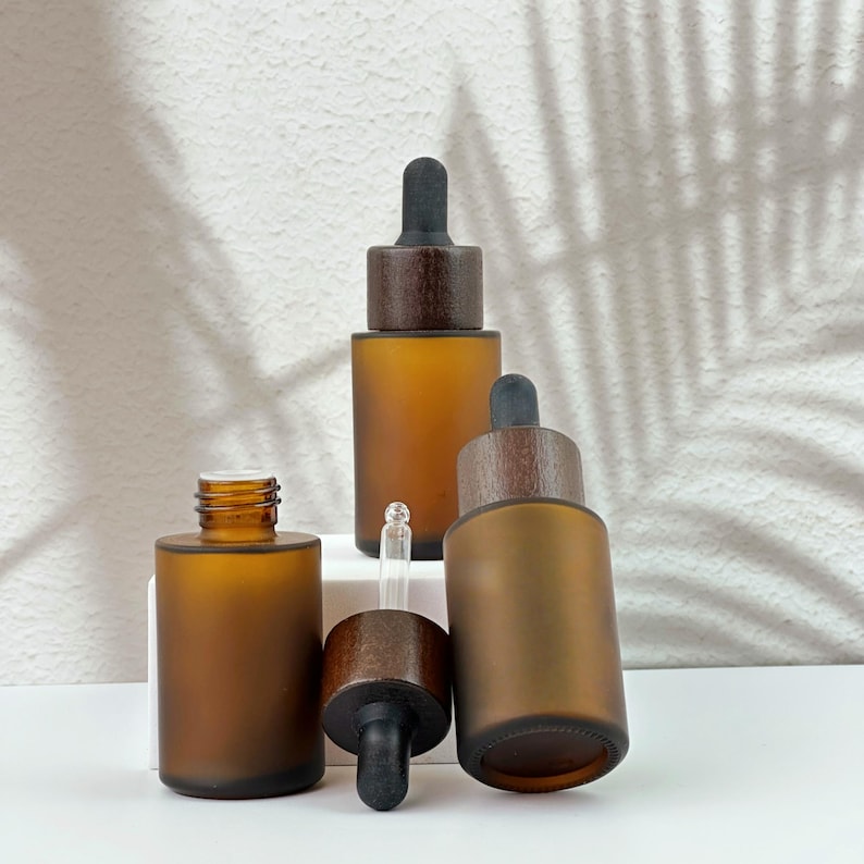 Three brown dropper bottles with natural wooden lids, arranged in an orderly manner, and the wooden lid of one of them has been removed.