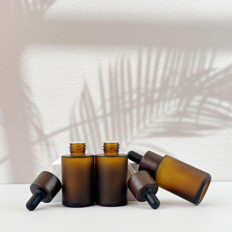 Three brown dropper bottles with natural wooden lids, arranged in an orderly manner, and the wooden lid of two of them has been removed.