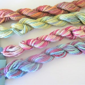 May include: Four skeins of embroidery floss in various shades of pink, green, blue, and yellow. The floss is twisted and has a variegated color pattern.