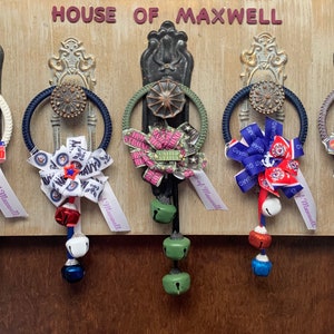 May include: Five door hangers with different ribbon designs and bells. The ribbons feature the words "House of Maxwell", "Navy", "Coast Guard", and "Hero".