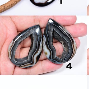 May include: Nine agate gemstone cabochons in a variety of shapes and sizes. The cabochons are black with white and grey banding and have a hollow centre.