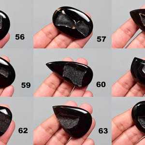 Op de afbeelding: Twaalf zwarte agaat cabochons met verschillende druzy patronen. De cabochons zijn allemaal van verschillende vormen en maten, maar ze zijn allemaal gepolijst en hebben een gladde, glanzende afwerking.