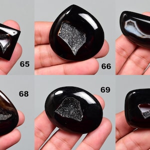 Op de afbeelding: Assortiment van tien zwarte agaat cabochons in verschillende vormen en maten. Elke cabochon heeft een uniek, natuurlijk, wit, kristallijn patroon.