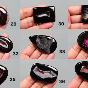 Op de afbeelding: Assortiment van negen zwarte agaat cabochons in verschillende vormen en maten. Elke cabochon heeft een uniek, natuurlijk gevormd, uitgehold centrum.
