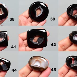 Op de afbeelding: Tien agaat cabochons in een zwart-wit kleurenschema. De cabochons hebben een gat in het midden en zijn omgeven door een witte rand. De cabochons zijn genummerd van 38 tot en met 46.