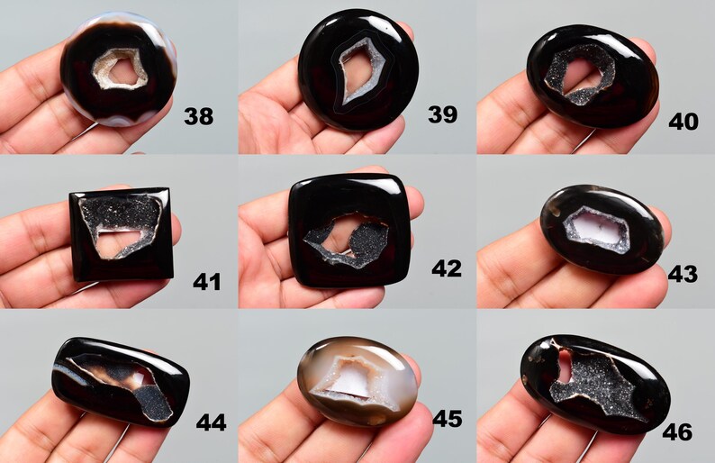 Op de afbeelding: Tien agaat cabochons in een zwart-wit kleurenschema. De cabochons hebben een gat in het midden en zijn omgeven door een witte rand. De cabochons zijn genummerd van 38 tot en met 46.