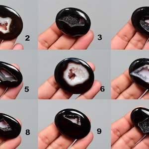 Op de afbeelding: Tien zwarte agaat cabochons met een wit druzy centrum. Elk cabochon is ovaalvormig en heeft een ander patroon van druzy.