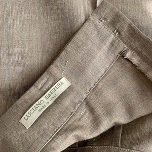 May include: A brown herringbone fabric with a white label that reads "Luciano Barbera Made in Italy".