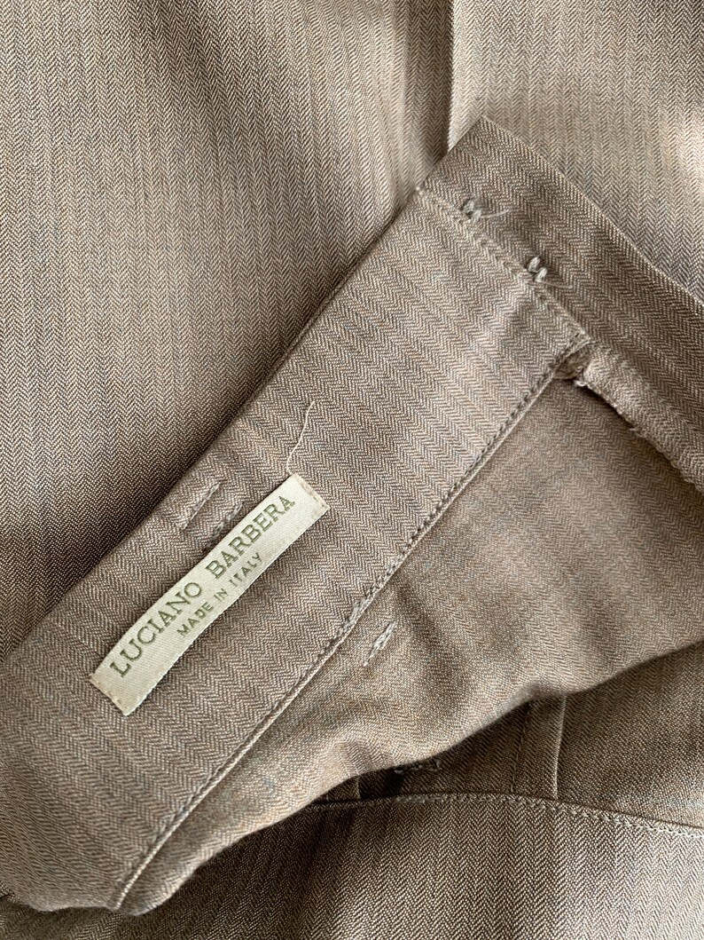 May include: A brown herringbone fabric with a white label that reads "Luciano Barbera Made in Italy".
