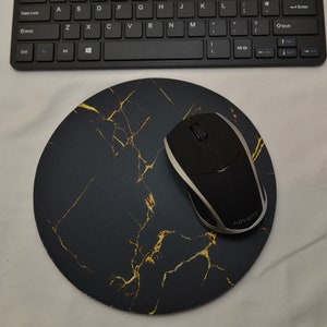 May include: A black and gold marble mouse mat with a black wireless mouse on top. The mouse has the word "ADVENT" printed on the side.