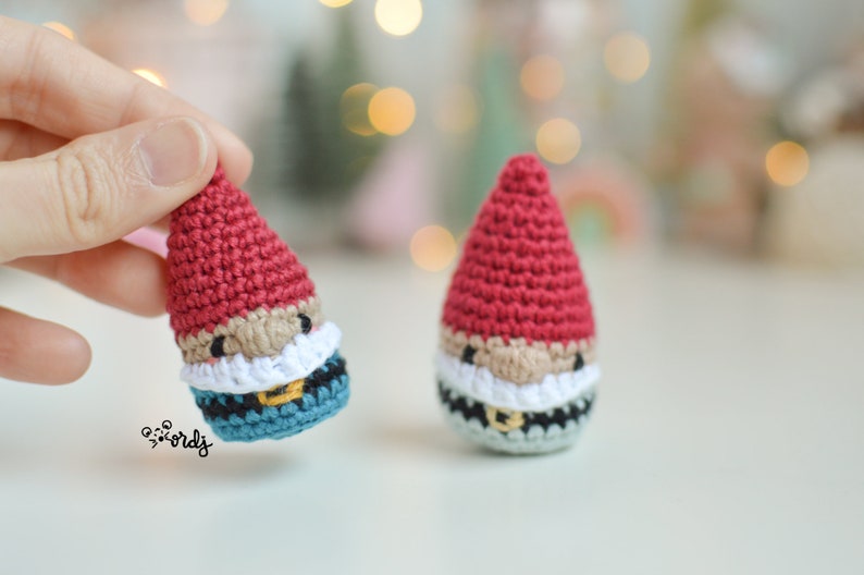 Op de afbeelding: Twee gehaakte gnomen met rode mutsen, witte baarden en zwarte riemen. De ene gnom heeft een blauw en zwart patroon, de andere een grijs en zwart patroon.