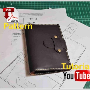 May include: A brown leather notebook with a yellow stitch and brass rivets. The notebook is on top of a white sheet of paper with a pattern for a leather notebook. The paper has the text "Pattern" and "Instructions" on it. The paper also has the text "Tutorial YouTube" on it.