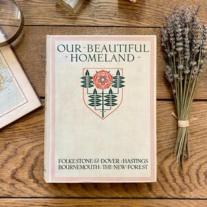 Può includere: Un libro vintage intitolato "Our Beautiful Homeland" con un design floreale verde e rosso sulla copertina. Il libro elenca le località Folkestone & Dover, Hastings, Bournemouth e The New Forest.