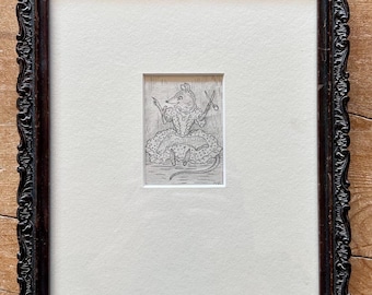 May include: A framed black and white etching of a mouse wearing a dress and holding scissors. The etching is set within a white mat and a dark, ornate wooden frame. The artwork is a whimsical illustration.