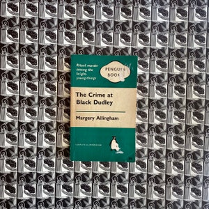 Puede incluir: Un libro de bolsillo Penguin Book verde con el t&iacute;tulo "The Crime at Black Dudley" de Margery Allingham. La portada presenta una ilustraci&oacute;n de ping&uuml;ino y el texto "Ritual murder among the bright-young-things".