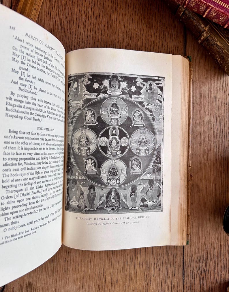 May include: A black and white illustration of a mandala with multiple circles and figures. The text "The Great Mandala of the Peaceful Deities" is printed below the image.