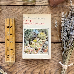 May include: A vintage book titled "The Observer's Book of Cacti & Other Succulents" by S. H. Scott. The cover features a colorful illustration of various cacti and succulents in pots.