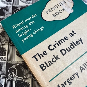 Puede incluir: Un libro de bolsillo Penguin con una cubierta verde y texto blanco. El t&iacute;tulo es "The Crime at Black Dudley" de Margery Allingham. El libro trata sobre un asesinato ritual entre los j&oacute;venes brillantes.