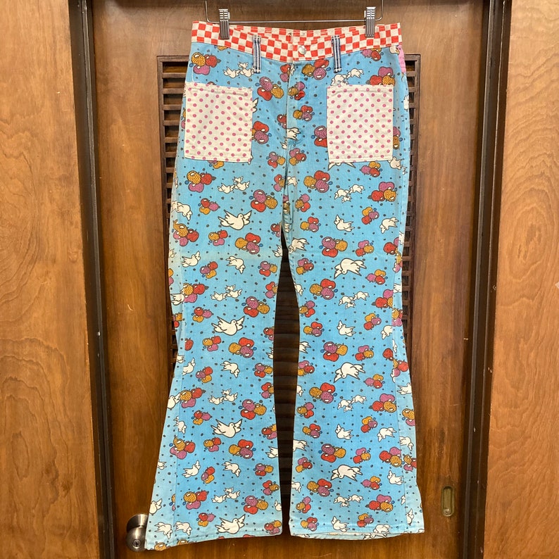 May include: Blue bell bottom pants with a white, red, and orange dove and balloon pattern. The pants have red and white checkered waistband and two pink polka dot pockets.