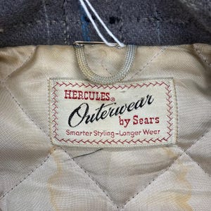 May include: A white label with red stitching and the text "Hercules&reg; Outerwear by Sears Smarter Styling - Longer Wear" on a quilted white fabric background.