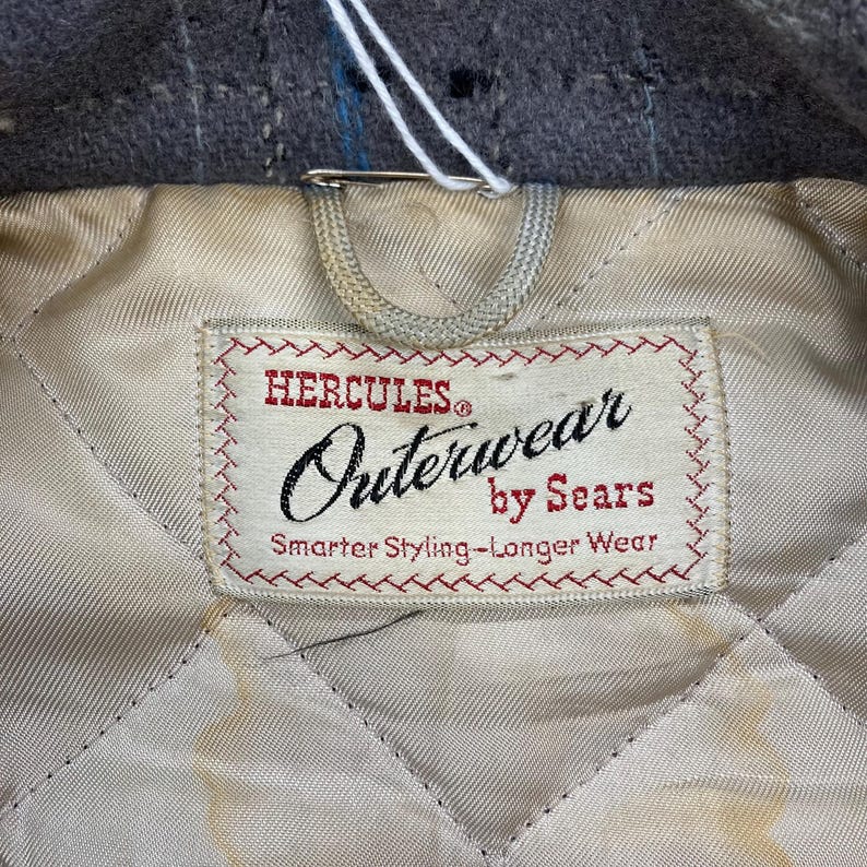 May include: A white label with red stitching and the text "Hercules&reg; Outerwear by Sears Smarter Styling - Longer Wear" on a quilted white fabric background.