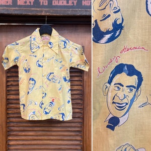 May include: A yellow short-sleeved button-down shirt with a repeating pattern of a man's face and the text "Wurley Herman".
