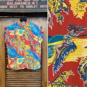 May include: A red short-sleeved shirt with a tropical print featuring palm trees, blue waves, and a woman in a hula skirt. The shirt has a button-up front and a collar.